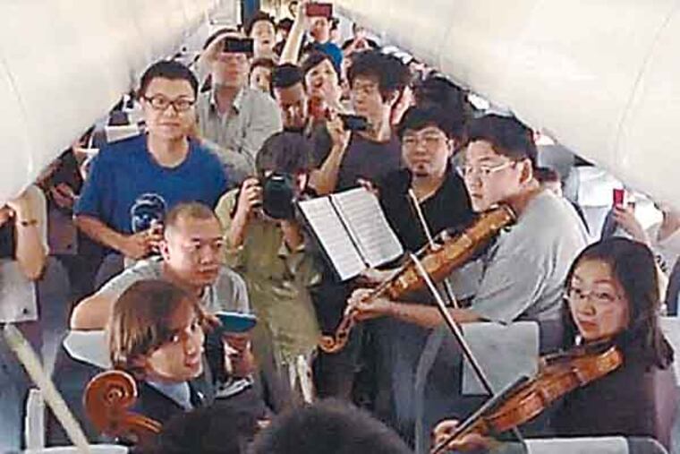 Still from video. Philadelphia Orchestra musicians perform on flight waiting on Beijing tarmac.