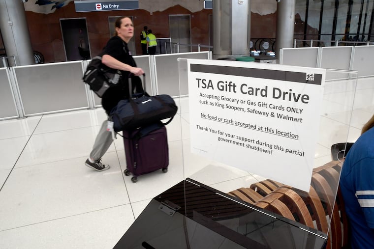A traveler walks past a gift card donation box for Transportation Security Administration officers at Denver International Airport on Friday, March 20, 2026.
