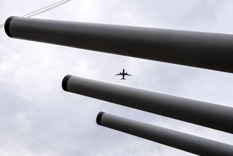 May 20, 2024: A plane taking off from Philadelphia International Airport flys over a turret of three 16-inch/50-caliber Mark 7 guns on the fore deck of the Battleship New Jersey.
