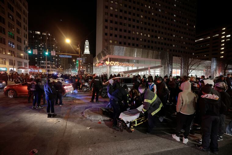 Police and emergency personnel assist people who were struck by a car at Broad and Spring Garden Streets during a postgame celebration Sunday.
