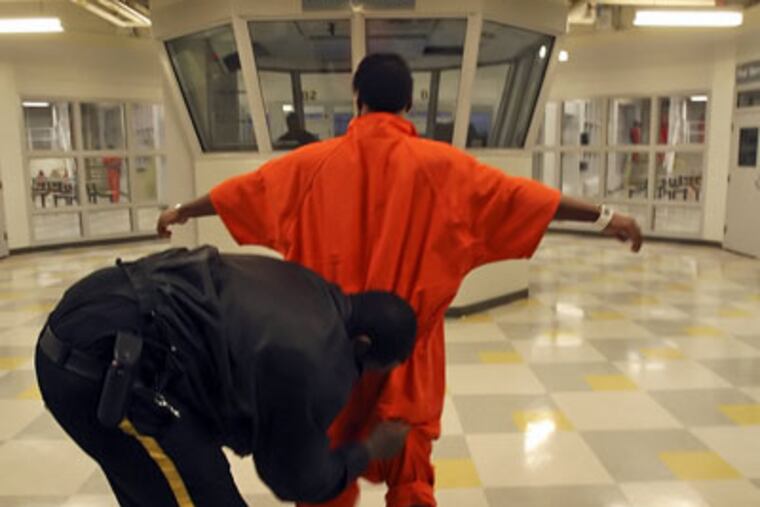 Guard pats down an inmate near the control tower at Curran-Fromhold, one of the city's six correctional facilities. (File Photo)