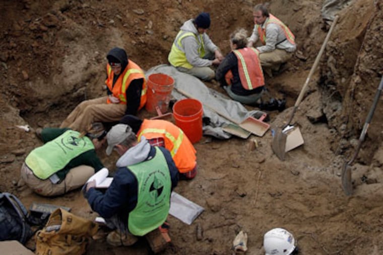 Archaeologists from Louis Berger Group dig at a grave site. (Akira Suwa / Staff Photographer )