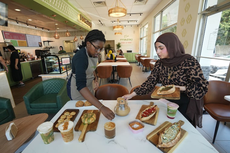 Baristas Michelle Lubrun (left) and Yasmeen Ghassam setting a table at Mazaj in Willow Grove.