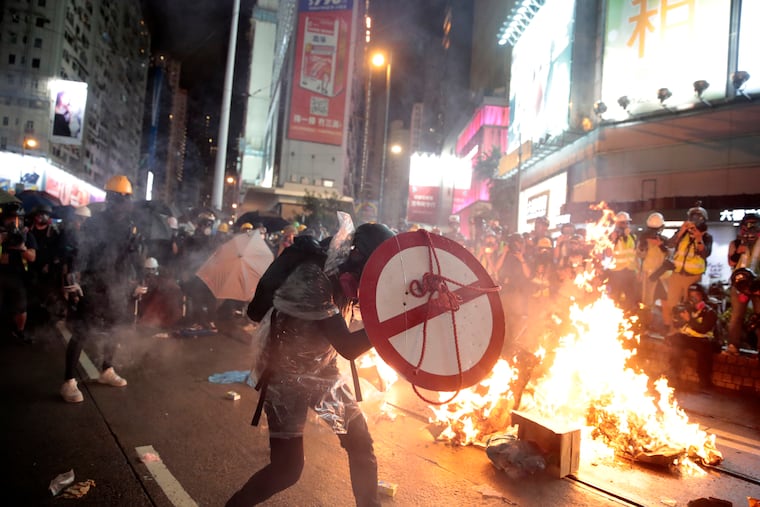 A protestor uses a shield to cover himself as he faces policemen in Hong Kong, Saturday, Aug. 31, 2019. Protesters and police are standing off in Hong Kong on a street that runs through the bustling Causeway Bay shopping district.
