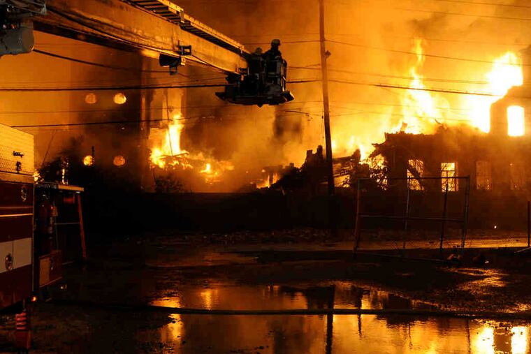 Oaklyn's tower ladder fights the warehouse fire from Jefferson Street. Other companies from around the region also responded.