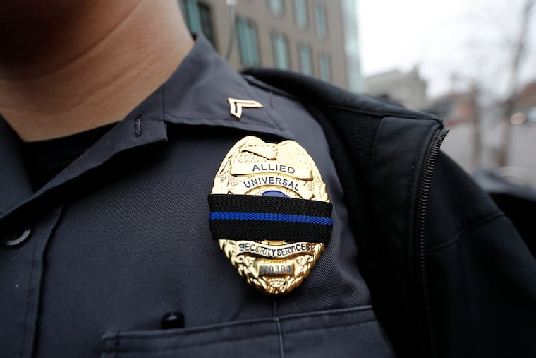 An officer from Allied Universal Security Service wears a band over his shield.