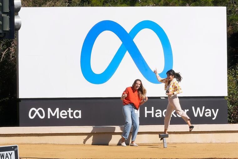 Facebook employees take a photo with the company's new name and logo outside its headquarters in Menlo Park, Calif., Thursday, Oct. 28, 2021, after the company announced that it is changing its name to Meta Platforms Inc. (AP Photo/Tony Avelar)