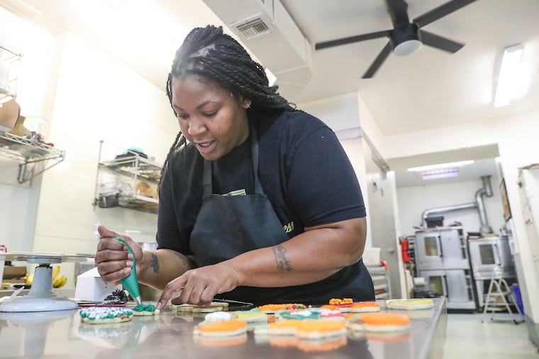 Pastry chef and cake-shop owner Tatiana Wingate demonstrating how to decorate a Christmas tree cookie at her shop, Sprinkled Sweetness, in Philadelphia on Oct. 14, 2022. Wingate is offering cookie-decorating classes for the holidays.