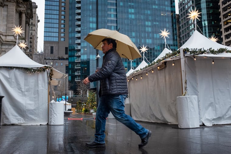 A pedestrian walks on a cold and rainy morning in the Christmas Village.