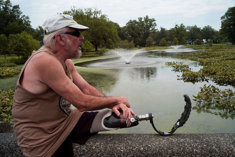 Joe Rusin of Haddon Township stretches on a bridge over Newton Lake. He lost a leg in a motorcycle accident, but still runs around the lake three to four times a week. "The algae is breaking up a little bit," he said.