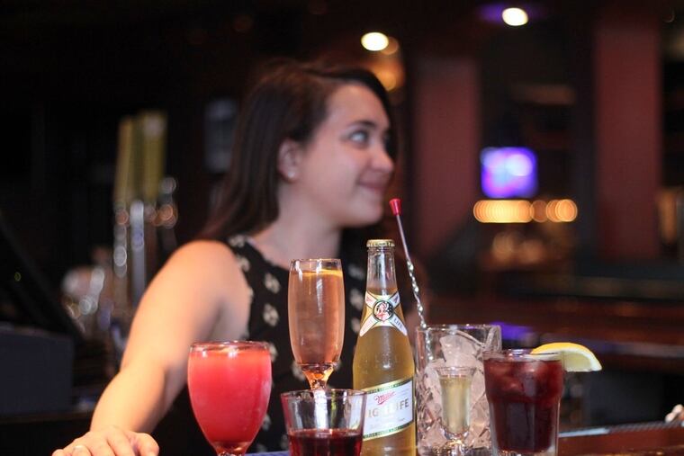 Cristina Tessaro with (from left) the cherry adult water ice; the house red wine; "The Hello, Suzy" (Cocchi Americana Rosa, Prosecco); a bottle of Miller High Life; a housemade limoncello; and a Limoncello Bramble (limoncello, Plymouth Combier Creme de Cassis) at Triangle Tavern, 10th and Reed Streets. ( Michael Klein / Philly.com )