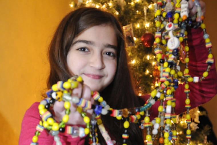 Julia Parmisciano holds her collection of courage beads she received during her stay at Children Hospital of Philadelphia while waiting for a new heart. Each bead represents any procedure done to her during her stay. (Ron Tarver / Staff Photographer)