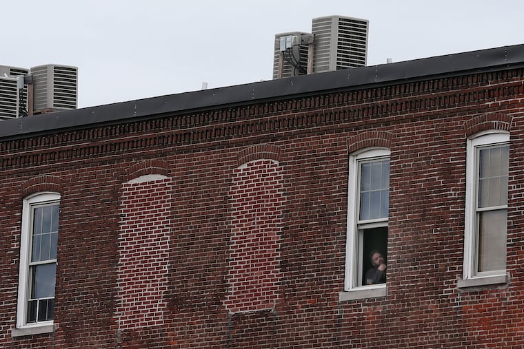 A man looks out of an apartment building in Philadelphia's Fishtown section on Wednesday, April 1, 2020. The city has directed residents to stay at home except for essential activities.
