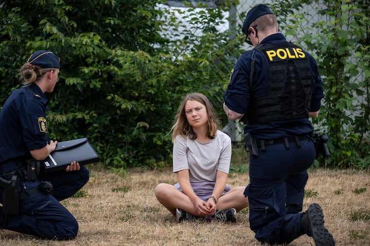Police officers talk to the Swedish climate activist Greta Thunberg as they move activists from the organization 'Ta Tillbaka Framtiden' (Take back the future) who are blocking the entrance to the Oljehamnen neighbourhood in Malmo, Sweden on June 19.