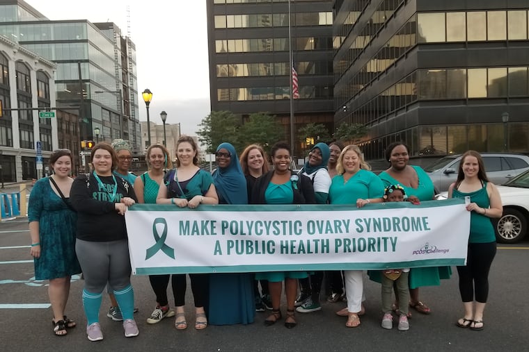 PCOS Challenge founder Sasha Ottey (center in black blazer) and her "cyster" activists met in Philadelphia in 2018. They gathered at the foot of the Philadelphia Electric Company building while its crown lights intermittently scrolled "World PCOS Day."