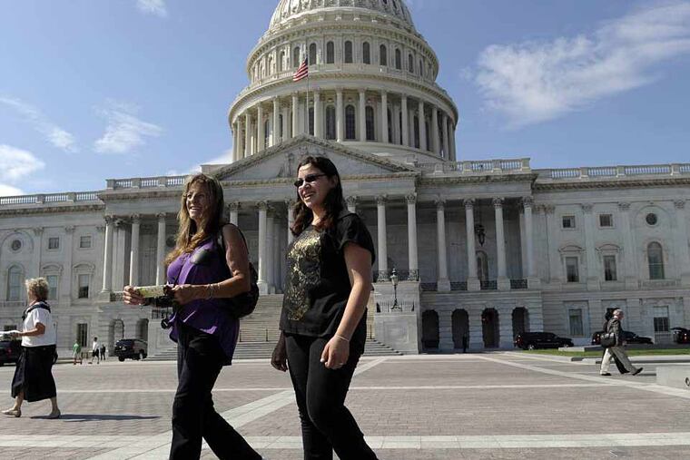 In this Oct. 1, 2013, photo, tourists Mary Avanti, left, and her granddaughter Galina, right, visit walk outside the U.S. Capitol in Washington. Tourists are pretty much locked out of Washington's monuments and museums, but those who want to hear lawmakers argue some more about the government shutdown are welcome to it. (AP Photo/Susan Walsh)