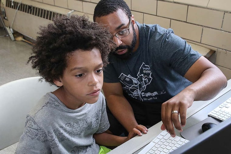 Sylvester Mobley works with Marlowe Whittenberg , 8, at a Coded by Kids workshop at the Marian Anderson Recreation Center. Coded by Kids is a nonprofit offering technology classes at city recreation centers for young people age 5 to 18.