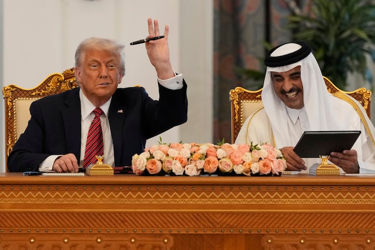 President Donald Trump holds up a pen given by Qatar's Emir Sheikh Tamim bin Hamad Al Thani as they exchange documents during a signing ceremony at the Amiri Diwan in Doha, Qatar, last week.
