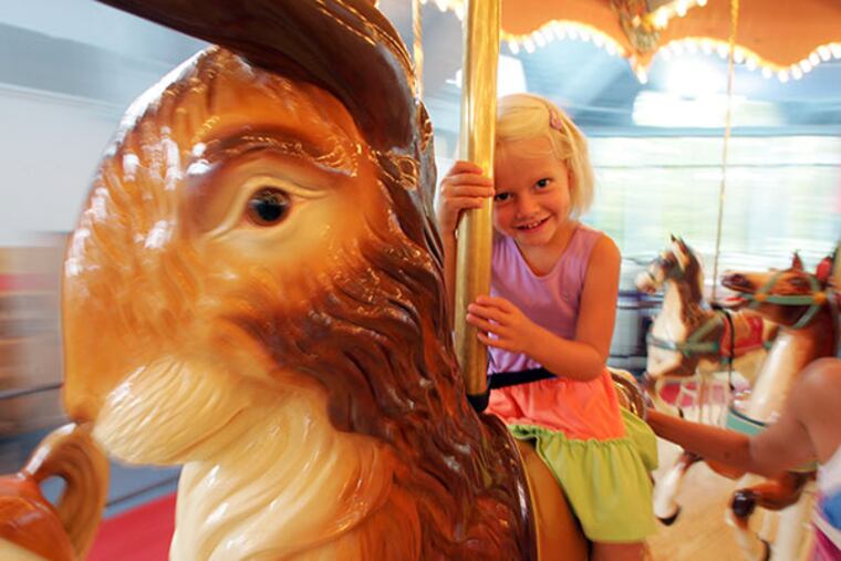 Camryn Thompson, 4, with her mother Jana rides the carousel at the Please Touch Museum. ( David Swanson / The Philadelphia Inquirer )