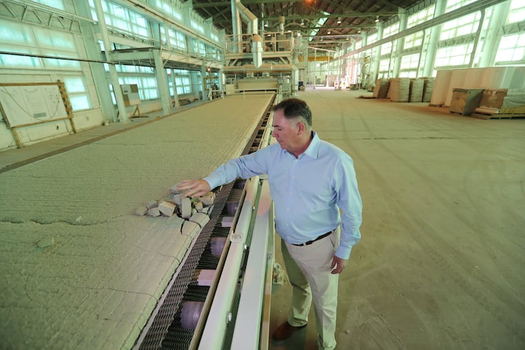 Thomas McGrath, president of AeroAggregates, samples the foamed glass aggregate after it emerges from a kiln, where it is made from recycled glass bottles.The company has installed a second kiln, doubling production.