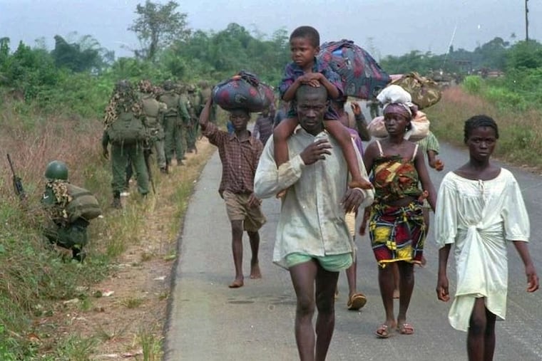 Civilians forced to flee their homes amid fighting during Liberia's first civil war pass West African peacekeeping forces on a road outside of Monrovia in 1995.