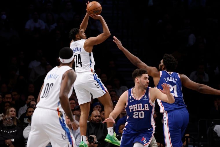 Cam Thomas (24) shoots as Joel Embiid defends on Saturday night. Embiid and the Sixers won, 101-98.