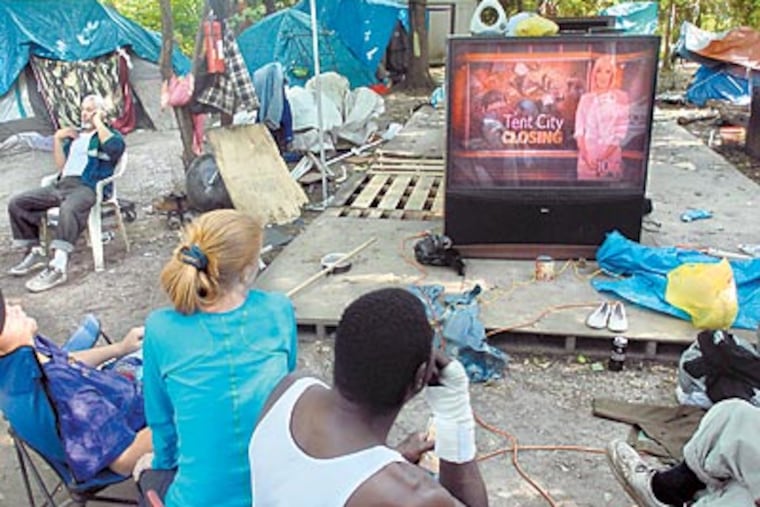 Tent City residents watch a news story about the closing of their community on their big-screen TV, which they found. (TOM GRALISH / Staff Photographer)