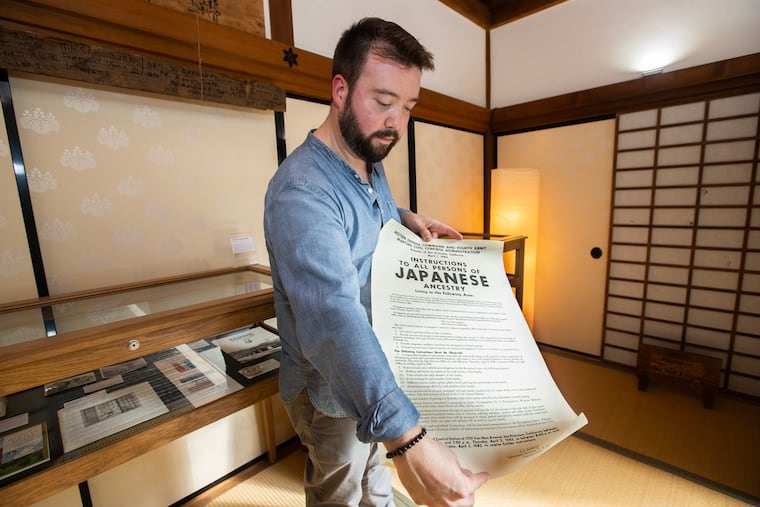 Rob Buscher, of the Japanese American Society of Greater Philadelphia, curated a new exhibit at the Shofuso Japanese House and Garden that explores the history and contributions of second-generation Japanese Americans through photo, video and audio storytelling. He is pictured on Aug. 10, 2023 holding a poster about the internment of Japanese Americans.