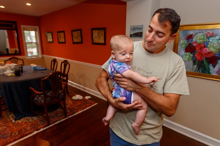 Brian Gralnick, who has De Quervain's tenosynovitis in his right wrist, cradles his daughter, Liv, 6 months old, in his home in Elkins Park on Oct. 1, 2019.