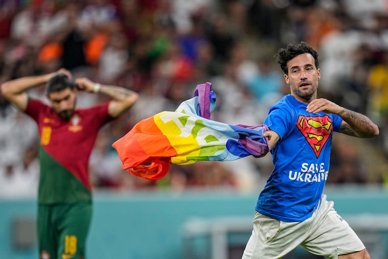 A pitch invader runs across the field with a rainbow flag during the World Cup group H soccer match between Portugal and Uruguay, at the Lusail Stadium in Lusail, Qatar on Monday.