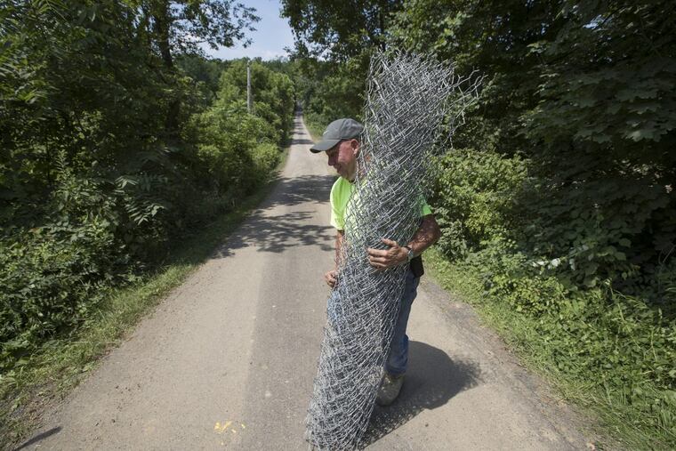 A crew from J. Cummings Construction Company works fencing off the driveway at the DiNardo property Thursday. Police have released the property, where Cosmo DiNardo is charged with murdering and burying four young men earlier this month, back to the family.