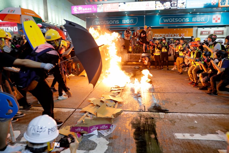 Protesters burn cardboard to form a barrier as they confront with police in Hong Kong on Saturday, Aug. 3, 2019. Hong Kong protesters removed a Chinese national flag from its pole and flung it into the city's iconic Victoria Harbour on Saturday, and police later fired tear gas at demonstrators after some of them vandalized a police station.