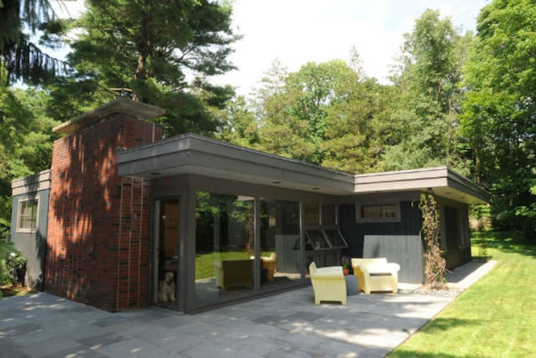 The glass front door is almost hidden by a glass wall off the patio, which is accentuated by two large yellow plastic "bubble" chairs. (BRADLEY C. BOWER / For The Inquirer)