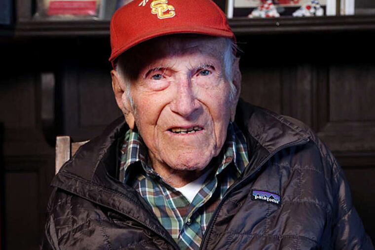 Louis Zamperini in January, holding a photo from his track days. (AP/USC)