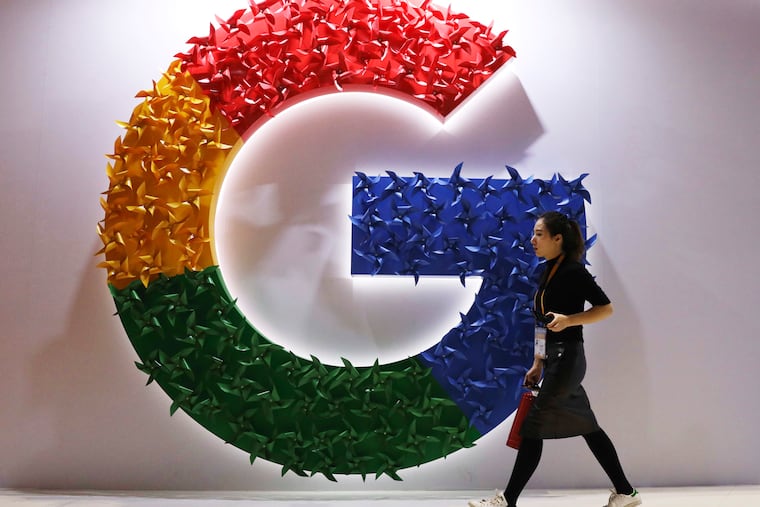A woman walks past the logo for Google at the 2018 China International Import Expo in Shanghai.