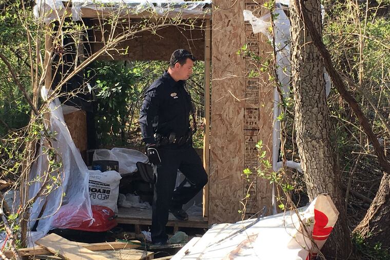 A Cherry Hill police officer checks out a makeshift shelter in the Colwick section of Cherry Hill. The discovery stunned residents who live nearby.
