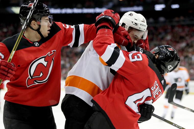Flyers defenseman Radko Gudas, center, of the Czech Republic, scuffles with New Jersey Devils left wing Brett Seney, right, during the second period of an NHL hockey game, Saturday, Jan. 12, 2019, in Newark, N.J. Devils' Blake Pietila, left, tries to intervene. (AP Photo/Julio Cortez)