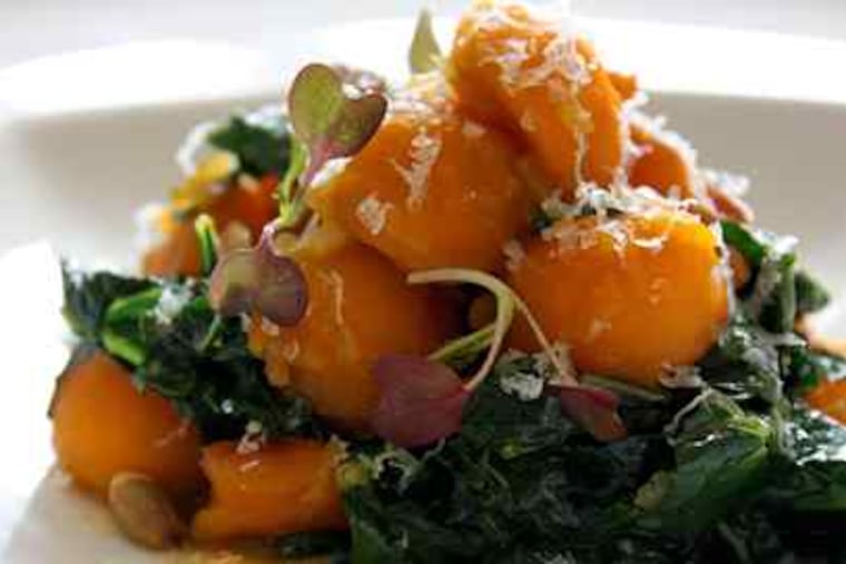 Kabocha squash with black kale at Jose Garces' JG Domestic at the Cira Centre. Right, a cassoulet of peanut-fing- erling potatoes, andou- ille sausage, braised cabbage, cheddar.