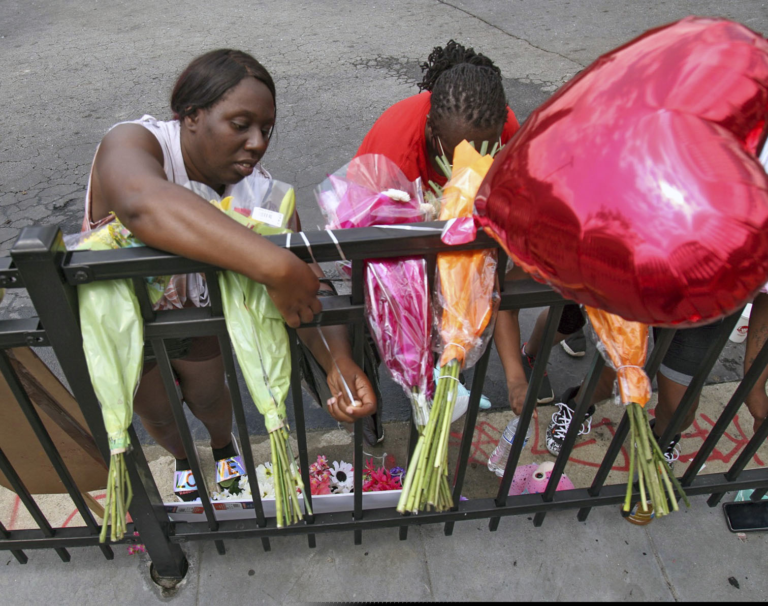 People attend to a memorial at the site of a destroyed Wendy's restaurant Sunday, June 14, 2020, in Atlanta. On Saturday, protestors set fire to the Wendy's where Rayshard Brooks, a black man, was shot and killed by Atlanta police Friday evening following a struggle in the drive-thru line.