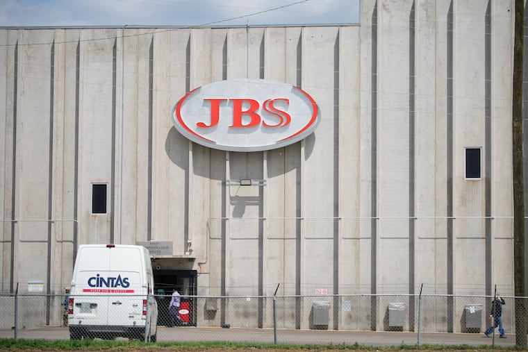 Employees walk in front of the entrance to the JBS meat processing plant in Greeley, Colo., in 2021.
