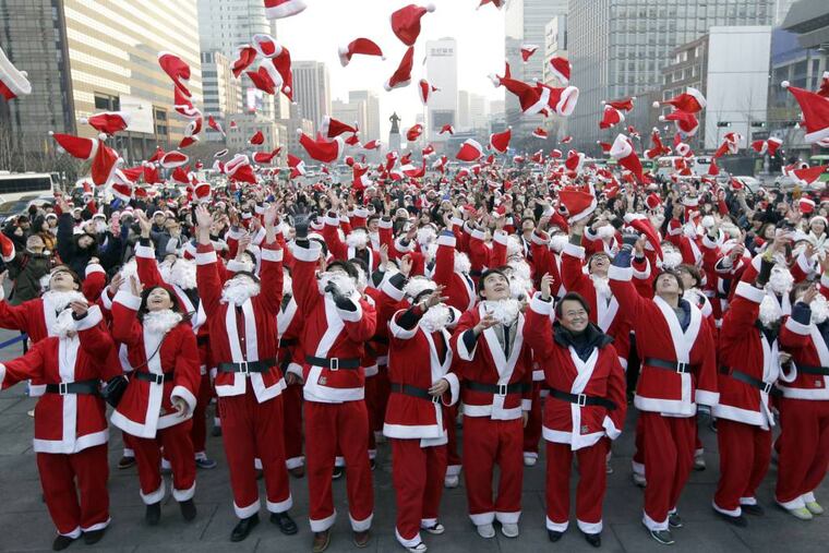 More than 1,000 volunteers clad in Santa Claus costumes throw their hats in the air as they gather to deliver gifts for the poor in downtown Seoul, South Korea, Tuesday, Dec. 24, 2013. (AP Photo/Lee Jin-man)