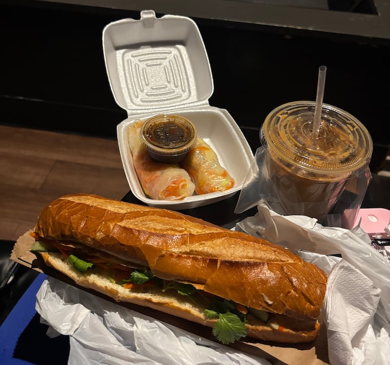 A chicken banh mi hoagie, veggie spring rolls, and a Vietnamese iced coffee from Banh Mi Cali that writer Hira Qureshi expertly snuck into the AMC Fashion District.