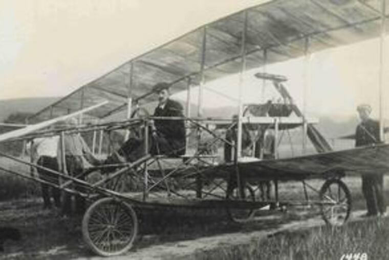 Glenn H. Curtiss, at right, awaiting takeoffon July 4, 1908, in Stony Brook Farm. Above, his wood-and-fabric biplane in flight.