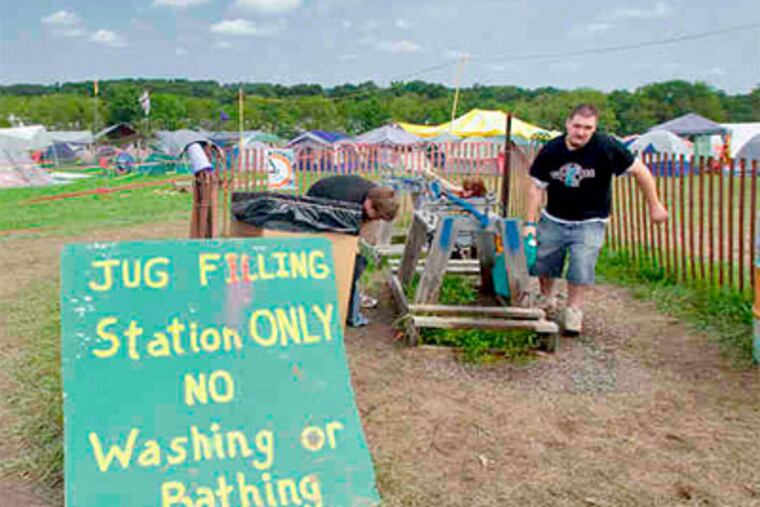 Solar power, recycling, and compostables are part of the go-green effort at the folk fest. An early arriver hauls water from a jug-filling station, where a sign warns against heavier usage. Ed Hille / Staff Photographer)