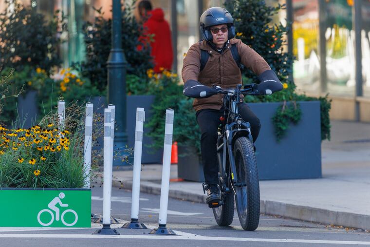 A cyclist rides an e-bike in designated bicycle lane along Market Street at 15th in Center City last week.