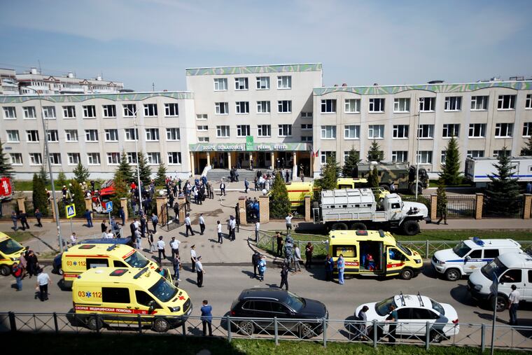Ambulances and police cars and a truck are parked at a school after a shooting in Kazan, Russia.