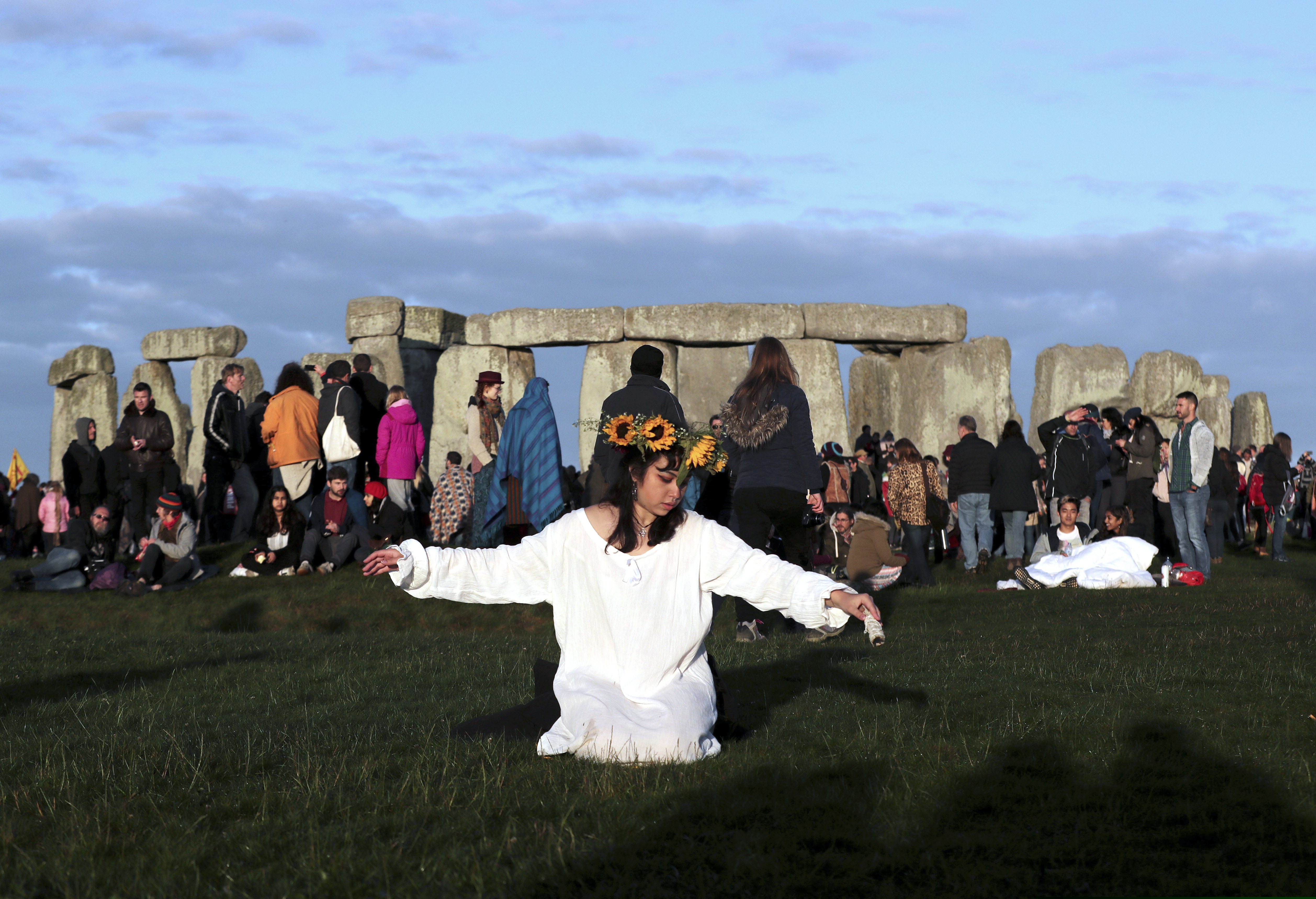 A reveler prays at sunrise as thousands gather at the ancient stone circle Stonehenge to celebrate the Summer Solstice, the longest day of the year, near Salisbury, England, Friday, June 21, 2019.