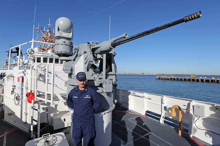 Petty Officer First Class Michael Henderson below an MK38 MOD 2 machine gun on the cutter Rollin Fritch.