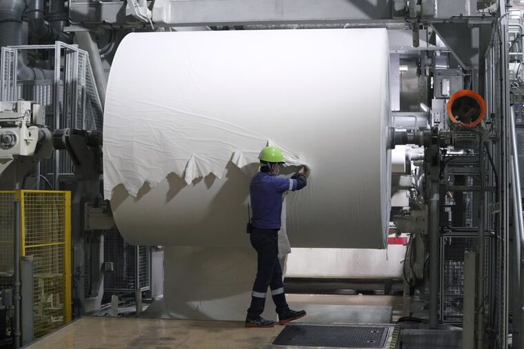 A worker checks a spool of recycled paper on the toilet paper production line at a Corelex Shinei Co. factory in Fuji, Shizuoka Prefecture, Japan.
