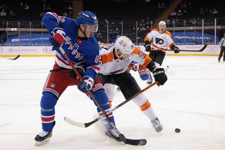 New York's Brendan Smith (left) and the Flyers' Claude Giroux fighting for a puck in the first period Monday. They'd meet again in the second when Smith decked Giroux with an open-ice check that the Flyers thought was a dangerous hit that should have been penalized.